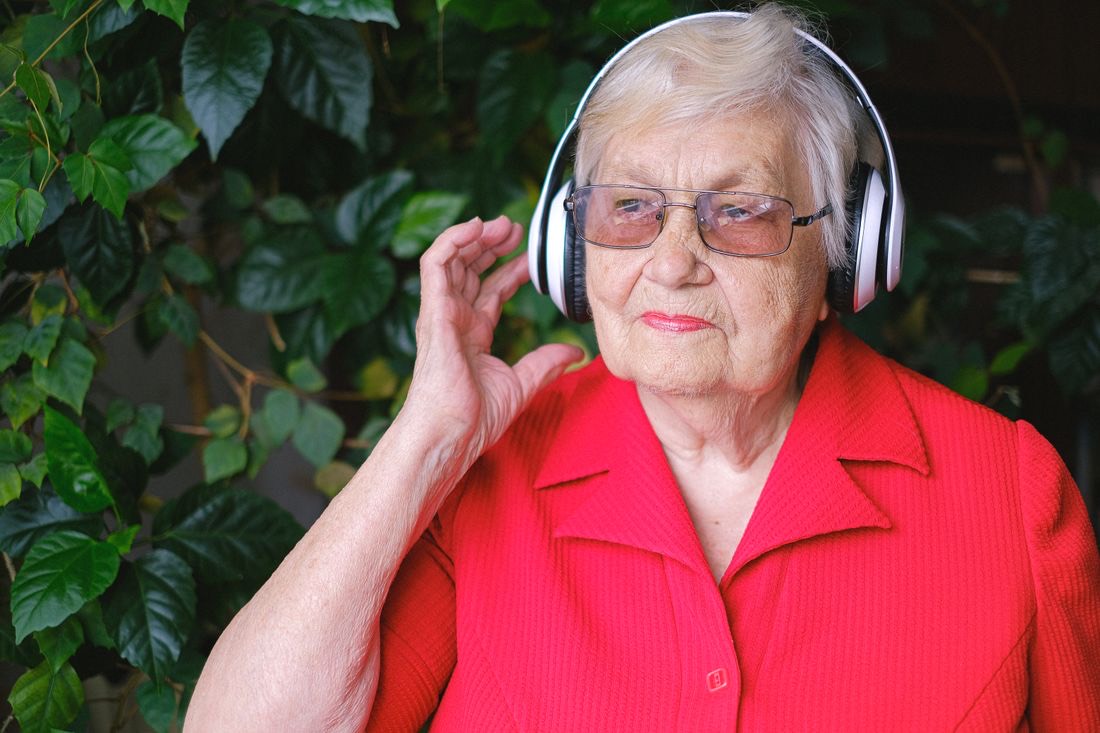 A resident enjoying music with headphones in her community's garden