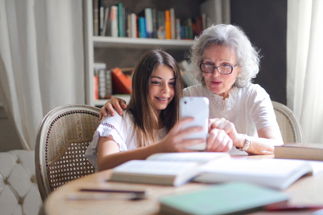 A grandmother and her granddaughter laughing at something on a phone